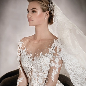 Elegante abito da sposa a maniche lunghe in pizzo con gonna a principessa e decoro di perle