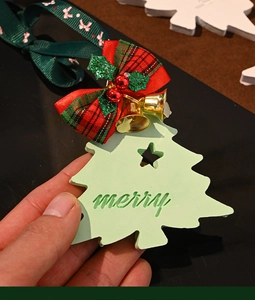 Close-up of a green plaster Christmas tree ornament with red ribbon and merry engraving