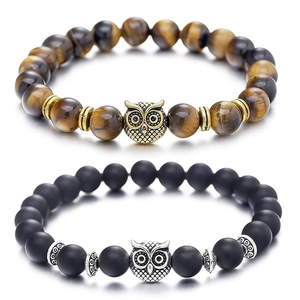 Close-up of beaded owl bracelets with tiger eye and matte black stones on reflective base