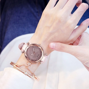 Close-up of rose gold watch with pink leather strap and matching star charm bracelet
