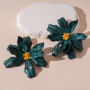 Macro detail of dark green acrylic flower earrings with vibrant orange beaded centers