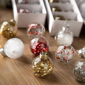 Transparent Christmas ball ornaments with festive glitters and feathers on wooden surface