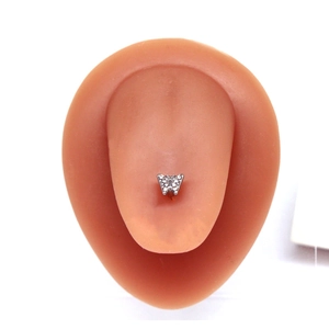 Gros plan détaillé d'un piercing de langue papillon argenté avec pierres sur modèle en silicone