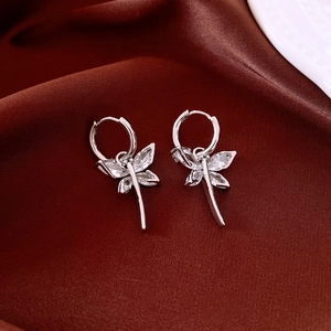 Detailed view of silver dragonfly hoop earrings with clear cubic zirconia on silk cloth