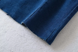 Detailansicht eines dunkelblauen Denim-Saums mit offenen Fransen und Doppelsteppnaht