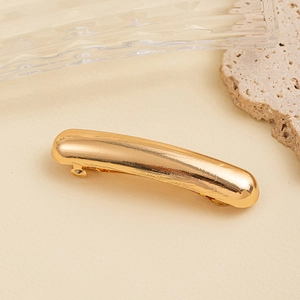 Close-up of minimalist gold metallic hair clip on aesthetic stone and glass background