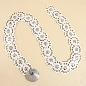 Detail view of white punk waist belt with silver metal grommets and embossed round buckle