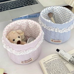 Detail of pink and blue quilted fabric storage baskets with lace trim on a clean desktop