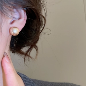 Close-up of elegant champagne gold pearl stud earring worn on a model's ear
