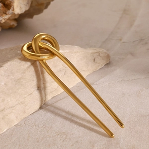 Detail of 18k gold plated stainless steel knot hair fork resting on natural stone