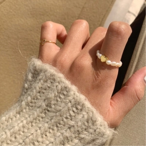 Detail of 925 sterling silver pearl heart ring and gold band set on soft fabric
