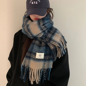 Detail of blue and beige plaid scarf showing soft wool texture and tassel trim