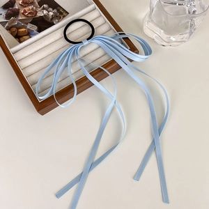 Detailed shot of light blue long ribbon hair tie with satin streamers on wooden display