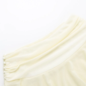 Detailed close-up of pleated cream-white chiffon top with matching fabric-covered buttons