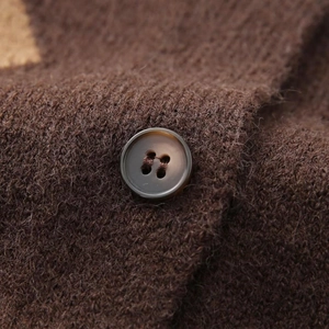 Makroansicht der dunkelbraunen Strickstruktur und Detailaufnahme des passenden Knopfes