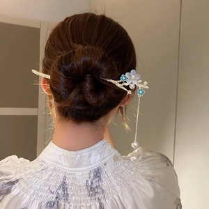 Épingle à cheveux fleurie avec perles et longs glands portés dans un chignon élégant