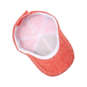 Detailed interior of a warm coral knit baseball cap showing secure white lining and seams