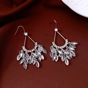 Macro shot of silver zircon drop earrings with leafy tassels on brown velvet surface