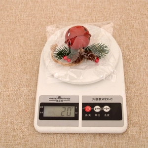 Close-up of a red Christmas bell with pine cones and berries on a digital scale
