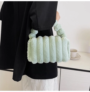 Close-up of soft light green plush handbag with vertical stripe texture and matching handle