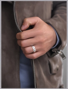Close-up of a men's vintage silver ring with engraved Sanskrit characters on a model's finger