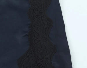 Nahaufnahme der schwarzen Spitzenborte und Satin-Textur an einem Minikleid
