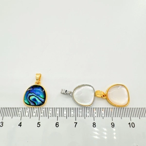 Close-up of heart shell pendants with measurement ruler showing various natural finishes