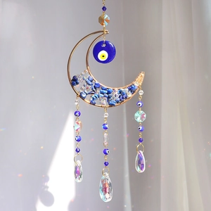 Blue Evil Eye moon suncatcher with crystal prisms and gold frame hanging in sunlight