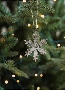 Detail of natural birch bark snowflake ornament hanging on a Christmas tree with bokeh lights