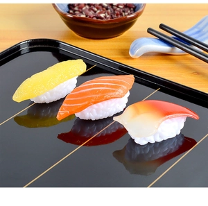 Detailed macro view of realistic PVC salmon and tuna sushi models on a glossy black tray