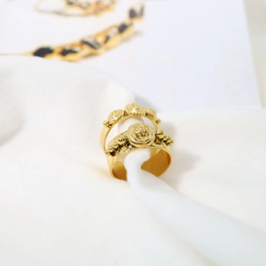 Macro view of vintage gold-plated rings featuring Medusa-style reliefs on white fabric