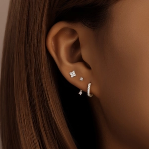Macro shot of a 925 silver earring set featuring a diamond flower and stud studs on the ear