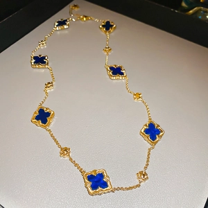 Detail view of gold-plated necklace with multiple blue clover motifs and dainty chain