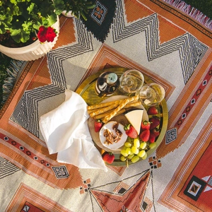 Ethnic bohemian picnic mat with colorful geometric patterns and tassels on green grass