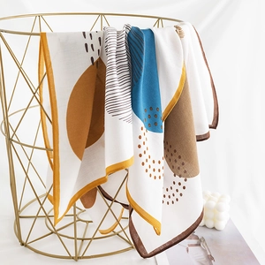 Elegant houndstooth and geometric silk scarf draped on a gold metal basket