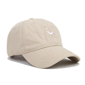 Close-up detail of soft cotton beige baseball cap with white smile face embroidery