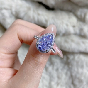 Macro shot of silver ring with pear-cut lavender stone and surrounding diamonds