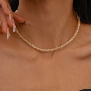 Close-up of a woman wearing a gold-tone mesh woven geometric choker with sparkling zircon