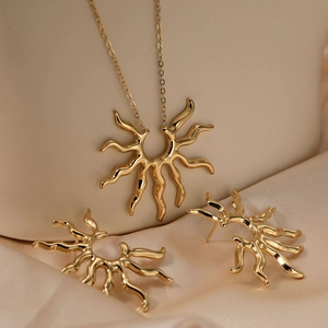 Golden 316 stainless steel sun-shaped necklace and earring set on champagne silk fabric