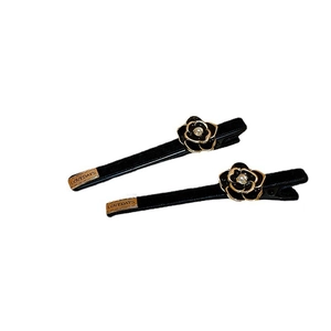 Elegant pair of black camellia flower hair clips with gold edges and pearl centerpieces