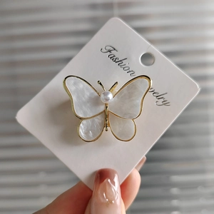 Elegant shell-textured butterfly brooch with gold edging and a pearl center accent