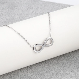 Detalle del collar plateado con símbolo de infinito y acabado de metal pulido liso