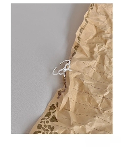 Artistic close-up of S925 sterling silver hollow bow ring on textured paper background