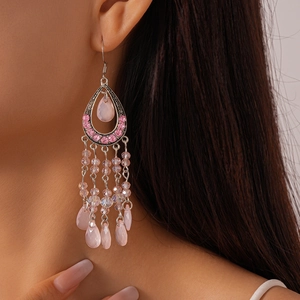 Macro detail of pink crystal teardrop earrings with elegant silver tassel chains
