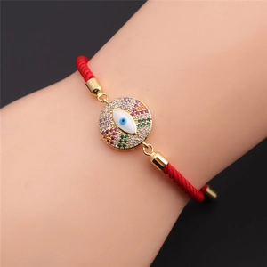 Detail of red braided Evil Eye bracelet with gold-plated charm and colorful rhinestones