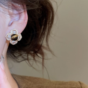 Close-up of vintage style 18k gold plated earring with tiger eye stone on female ear