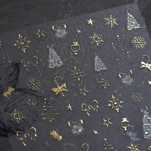Christmas gold foil nail stickers with stars and snowflakes on a dark textured background