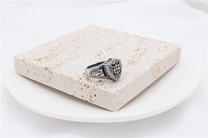 Macro view of vintage stainless steel shield ring featuring cross and feather texture