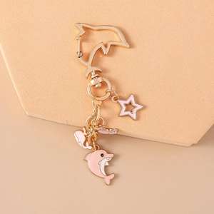 Detailed view of a golden dolphin keychain with pink enamel charms and a star pendant