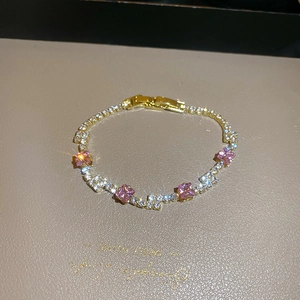 Close-up of gold chain bracelet featuring square pink stones and pave-set zircons